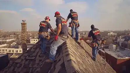 Experienced roofers replacing old shingles on a suburban house